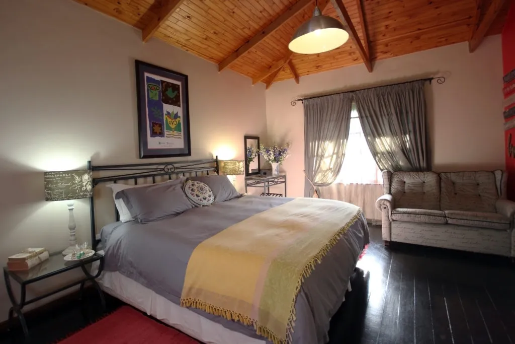 Cozy bedroom with large bed sofa and wooden ceiling