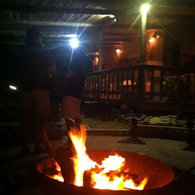 People gathered around a fire pit at night on a patio