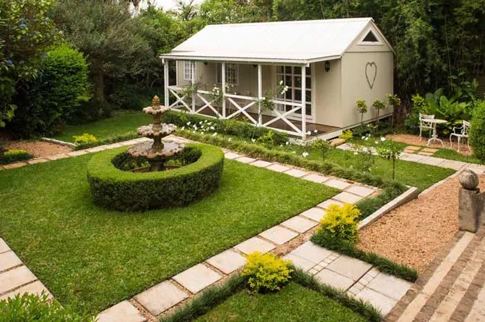 Small white cottage with a heart on the door in a wellmaintained garden