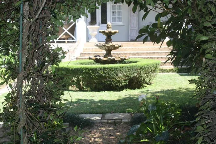 Stone fountain surrounded by greenery in a garden with steps in the background