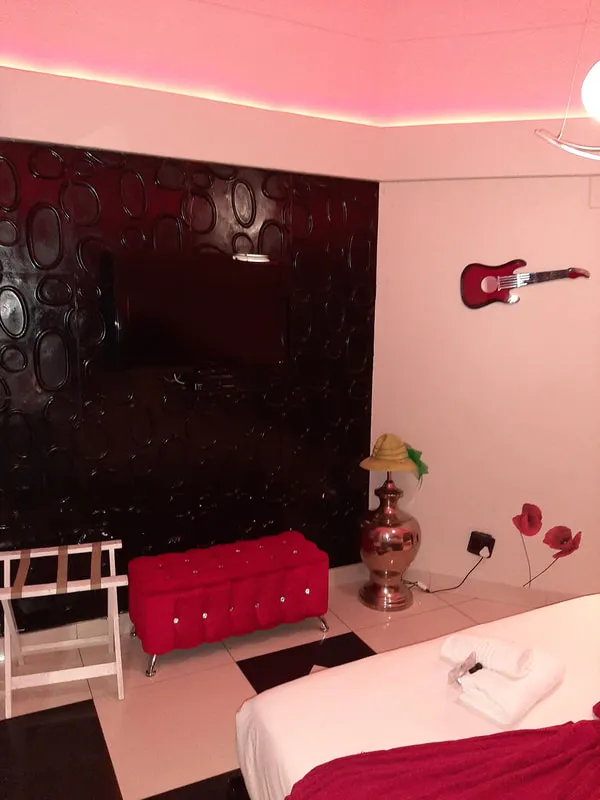 Bedroom with red bench TV guitar on wall and decorative elements