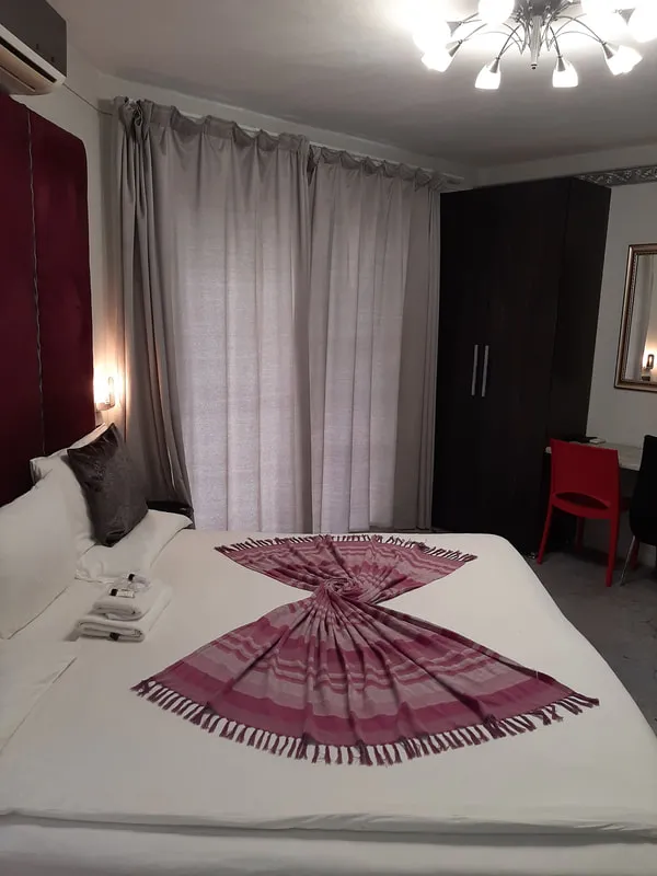 Bedroom with neatly made bed wardrobe and window with curtains