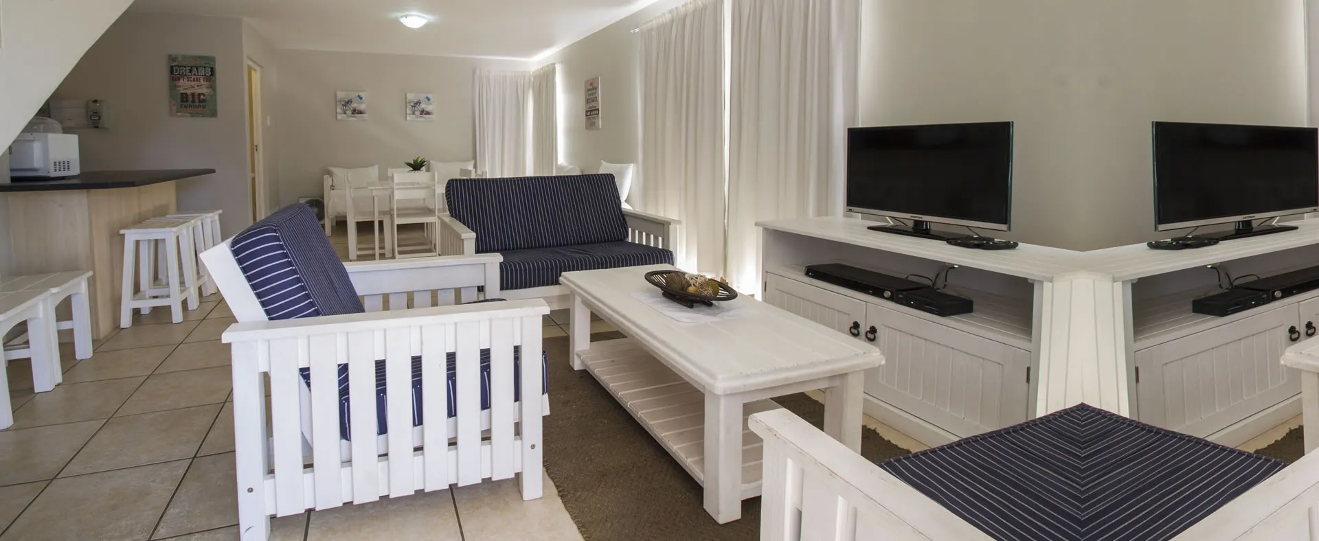 Modern living room with white furniture blue cushions and two TVs