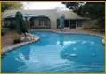 Swimming pool in a backyard with surrounding buildings and trees