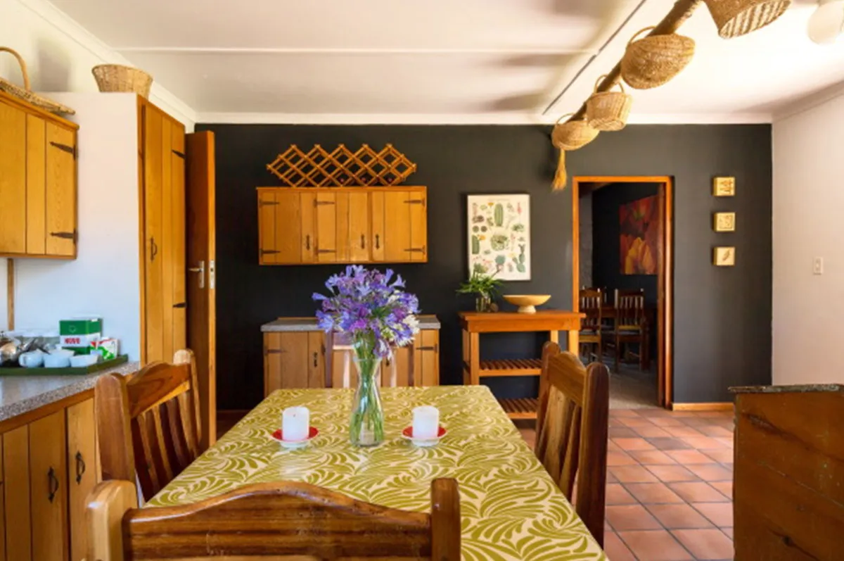 Wooden kitchen with yellow tablecloth purple flowers and dark green walls