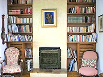 Two armchairs in front of a fireplace with bookshelves on either side