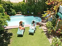 Two people relaxing by a pool in a lush garden setting