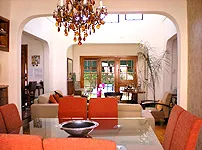 Living room with chandelier large windows and dining table with red chairs