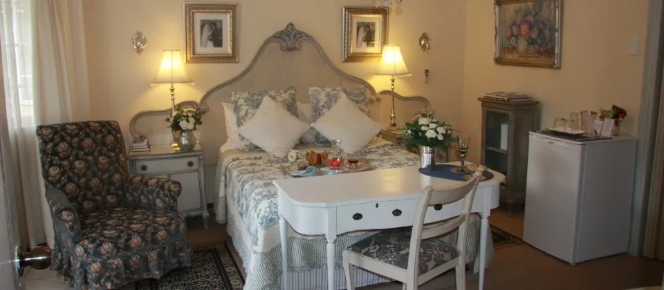 Cozy bedroom with a large bed desk chair and floral decor