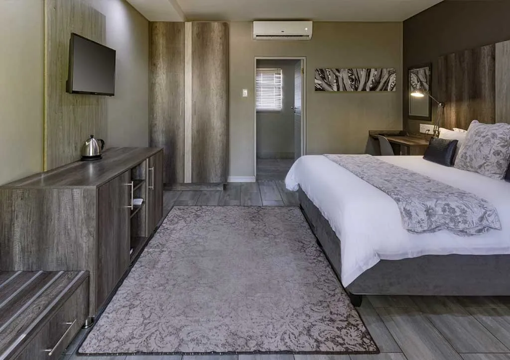 Modern hotel room with a large bed TV desk and wooden decor