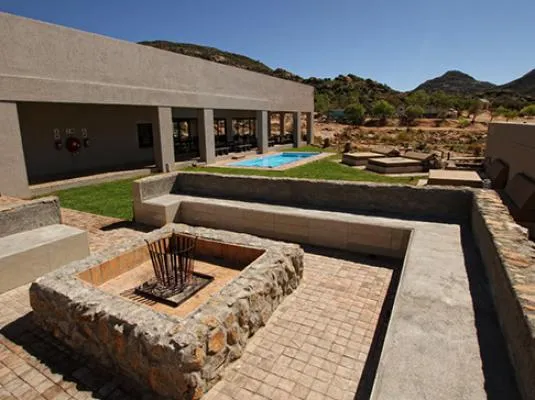 Outdoor seating area with fire pit pool and desert landscape in the background