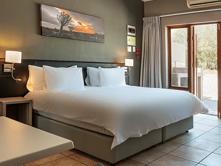 Neatly made bed in a modern bedroom with large window and artwork