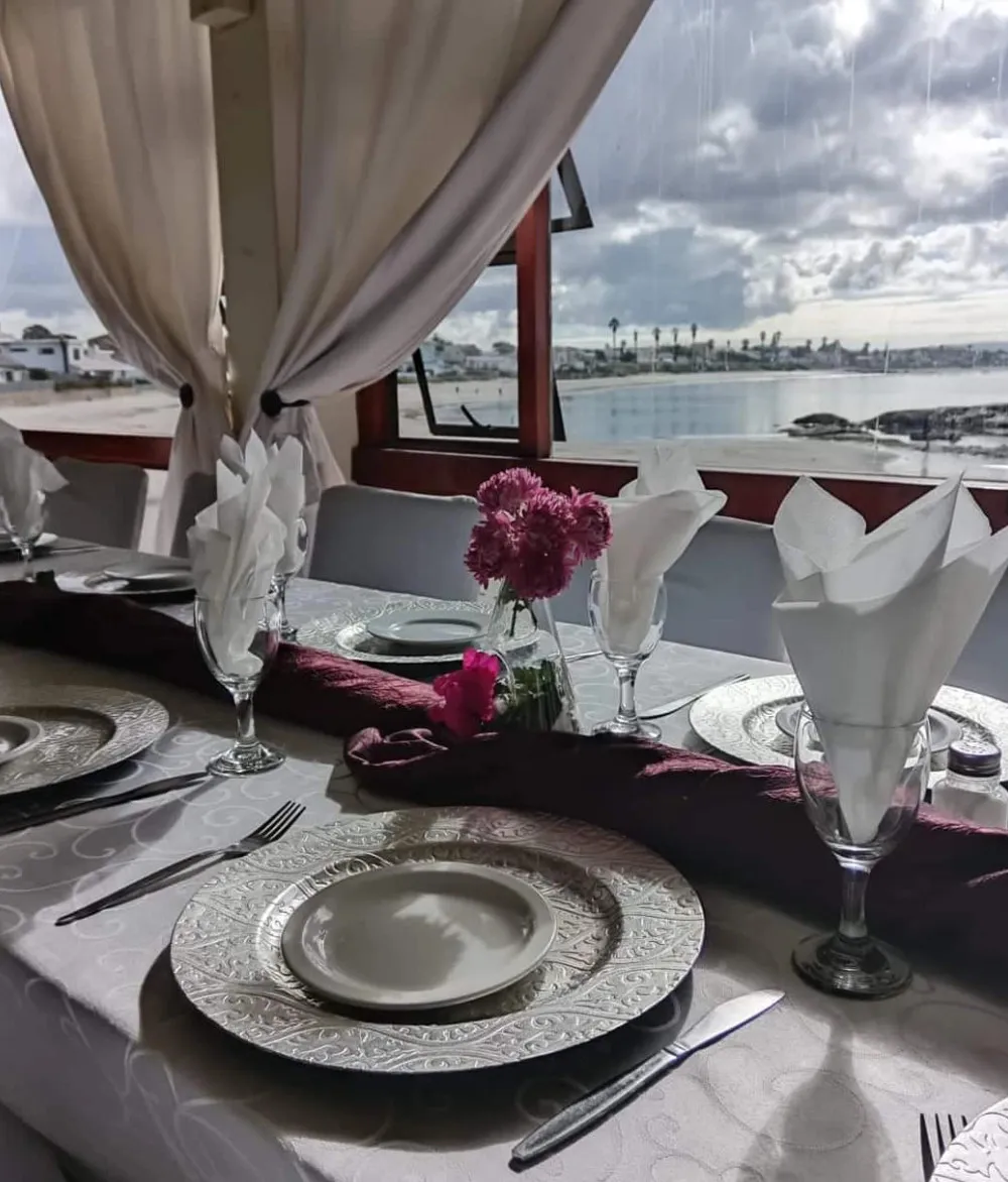 Elegant table setting with ocean view and pink flowers on the table