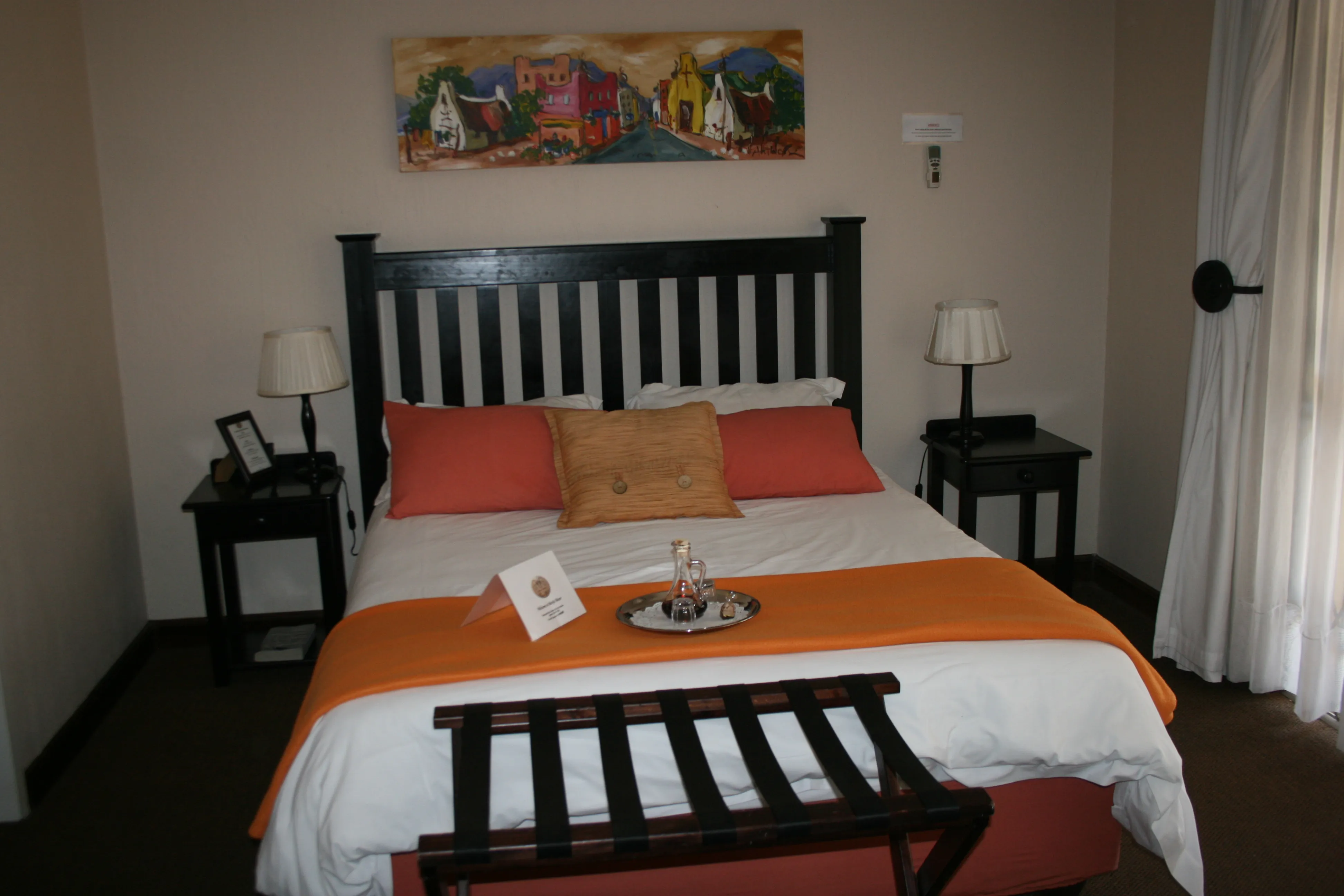 Bedroom with a bed orange and white bedding and a painting on the wall