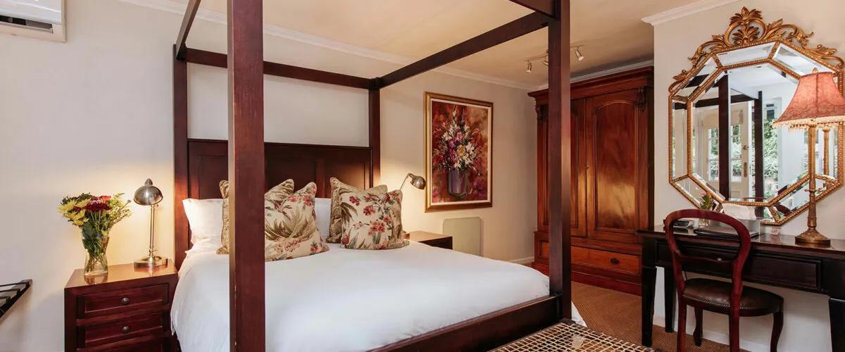 Cozy bedroom with a fourposter bed floral decor and a wooden dresser