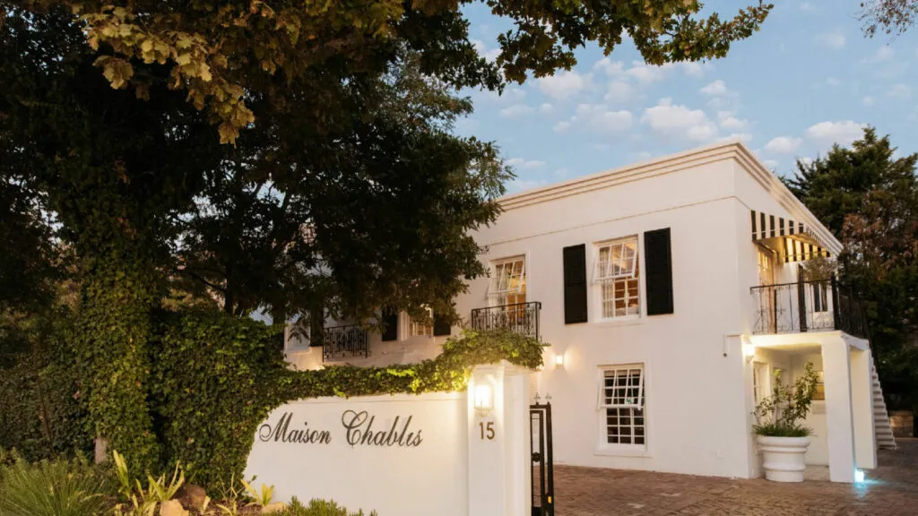 White building with Maison Chablis sign surrounded by greenery and trees