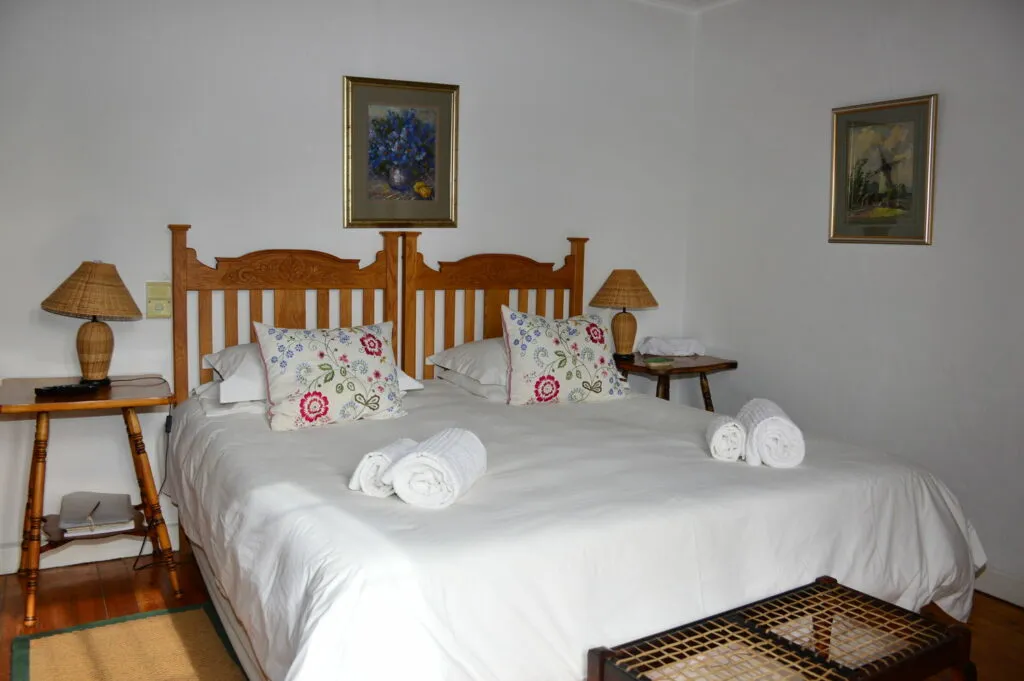 Neatly made bed with floral pillows and rolled towels in a tidy bedroom