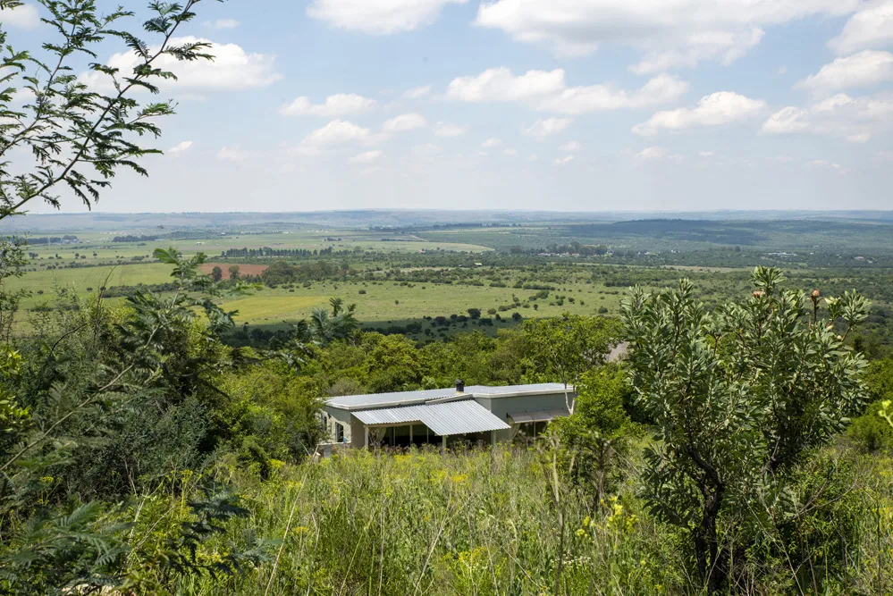 House on a hill overlooking a vast green landscape with scattered trees