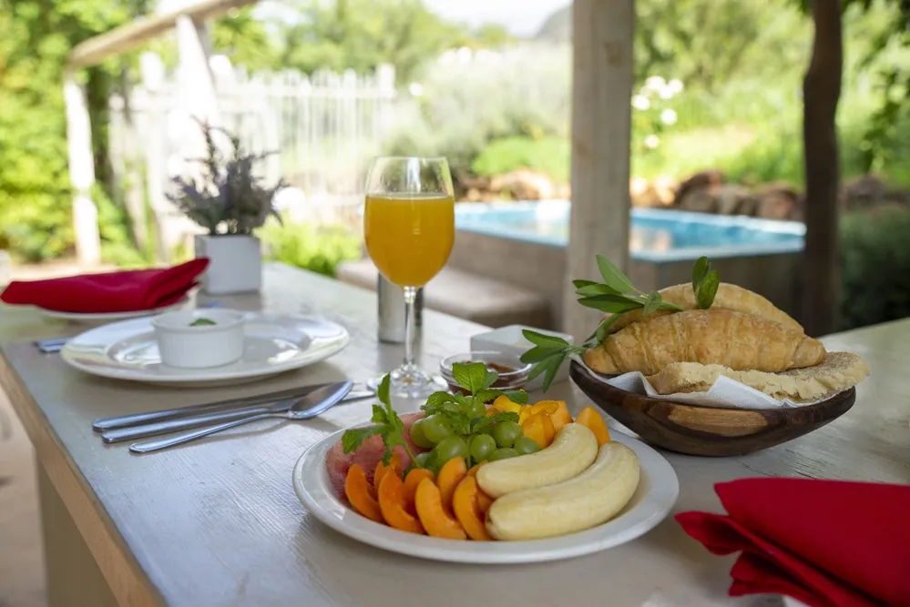 Breakfast setup with fruit croissants juice and outdoor pool view