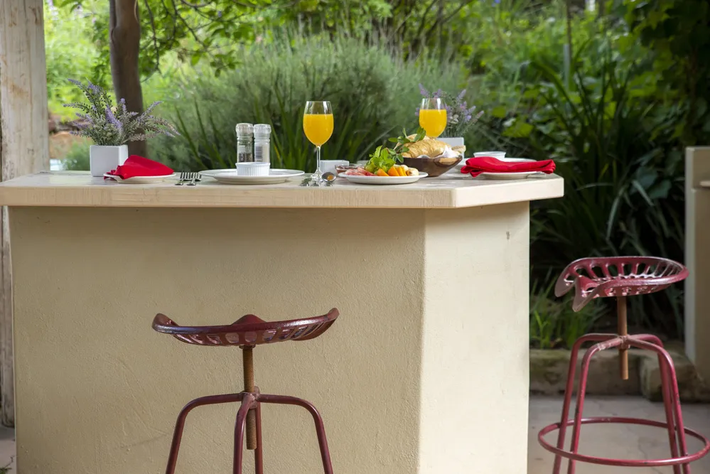 Two bar stools at a counter with food and drinks garden background