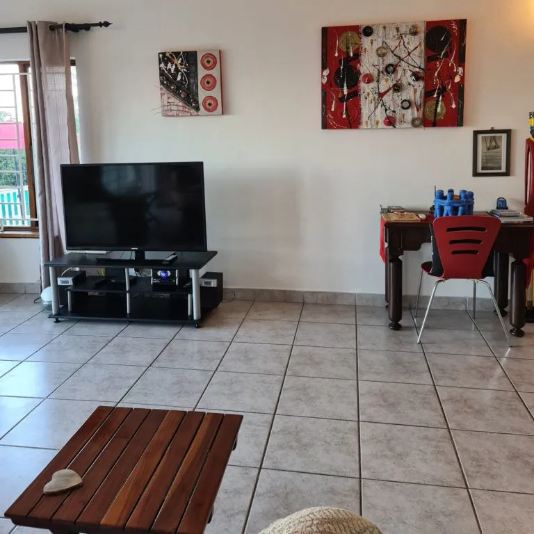 Living room with TV desk chair and abstract wall art on tiled floor