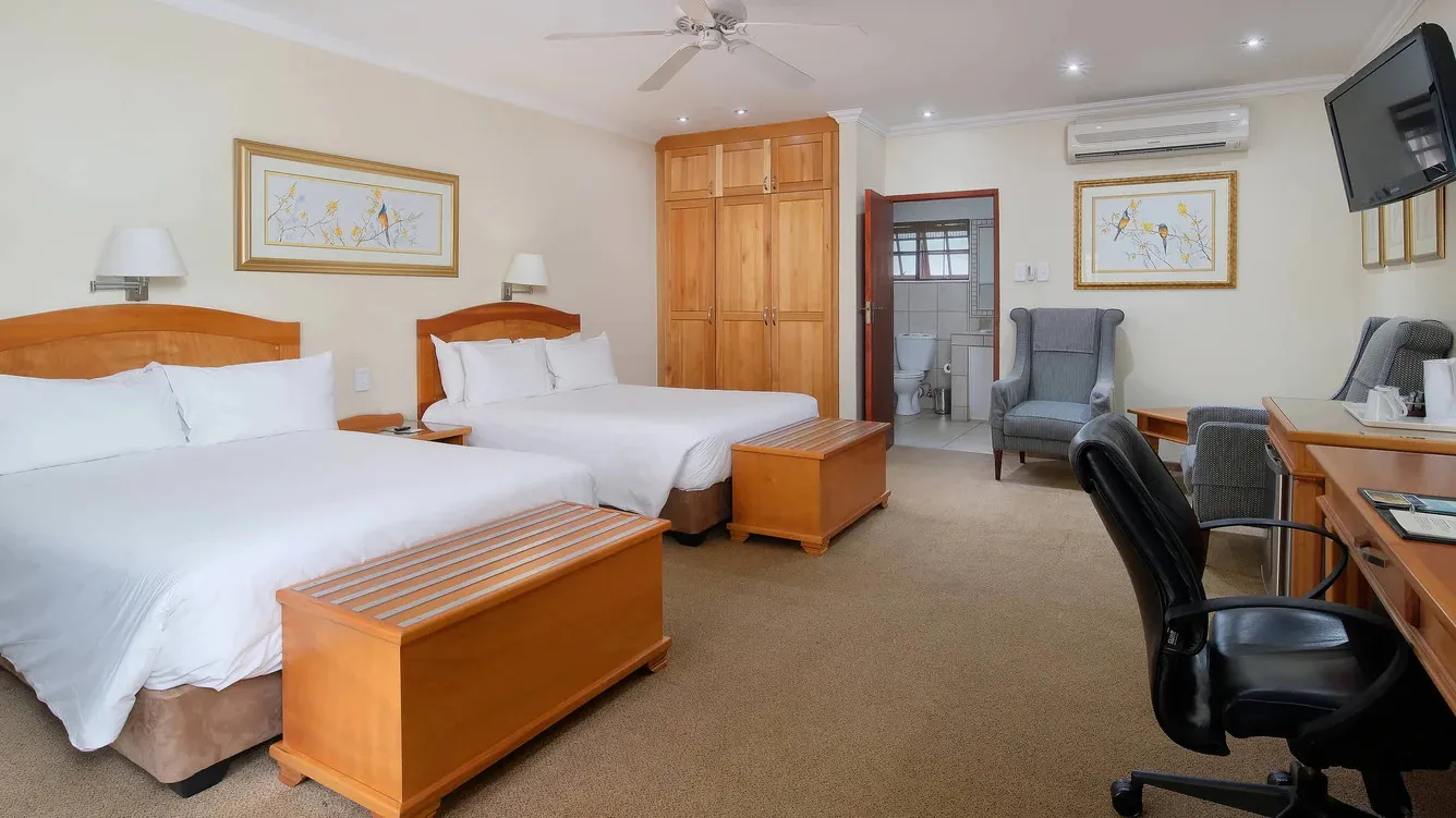 Hotel room with two beds desk chair and wooden furniture