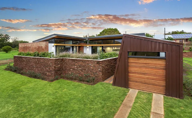 Modern house with sloped roof and wooden garage door in a grassy landscape