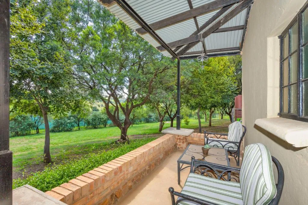 Patio with chairs table and a view of green trees and grass