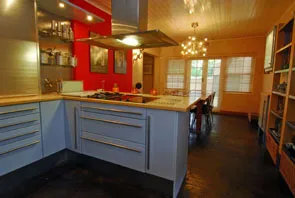 Modern kitchen with red wall wooden ceiling and dining area with large windows