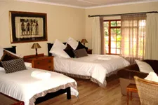 Bright bedroom with two beds wooden furniture and large windows with curtains