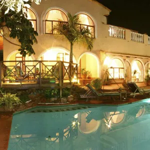 Night view of a lit villa with a swimming pool and palm trees