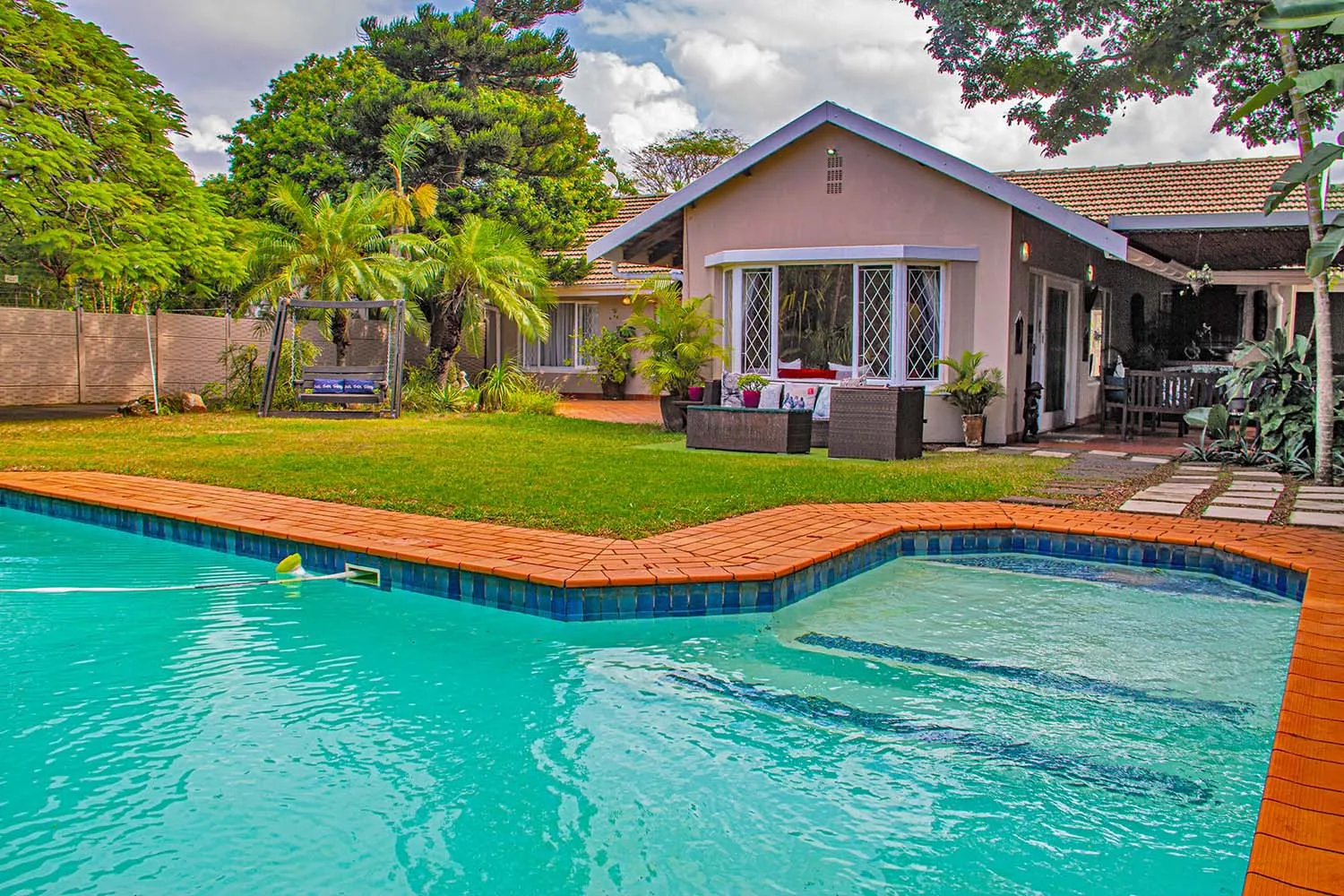 House with a pool garden and patio furniture in a tropical setting
