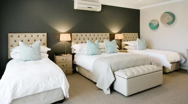 Three beds in a modern bedroom with dark green walls and neutral decor
