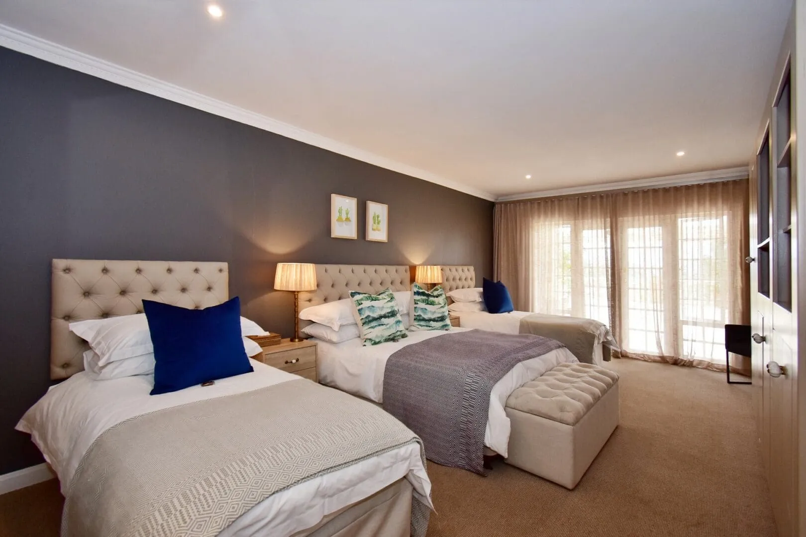 Bedroom with two beds upholstered headboards and large windows with curtains