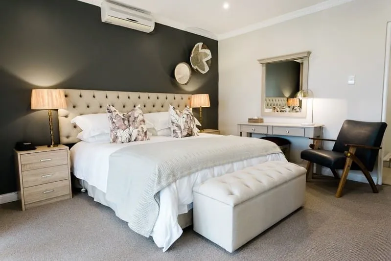 Modern bedroom with large bed side tables armchair and vanity