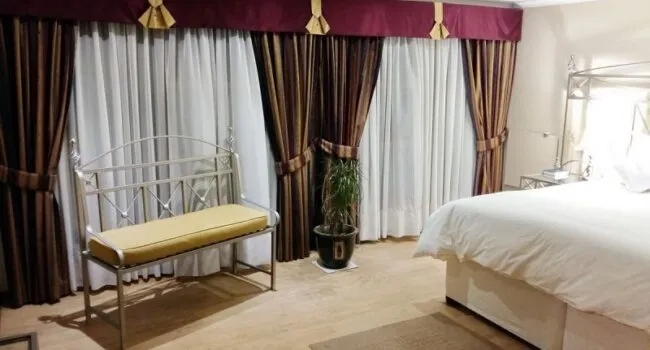 Bedroom with a bench potted plant and large windows with curtains