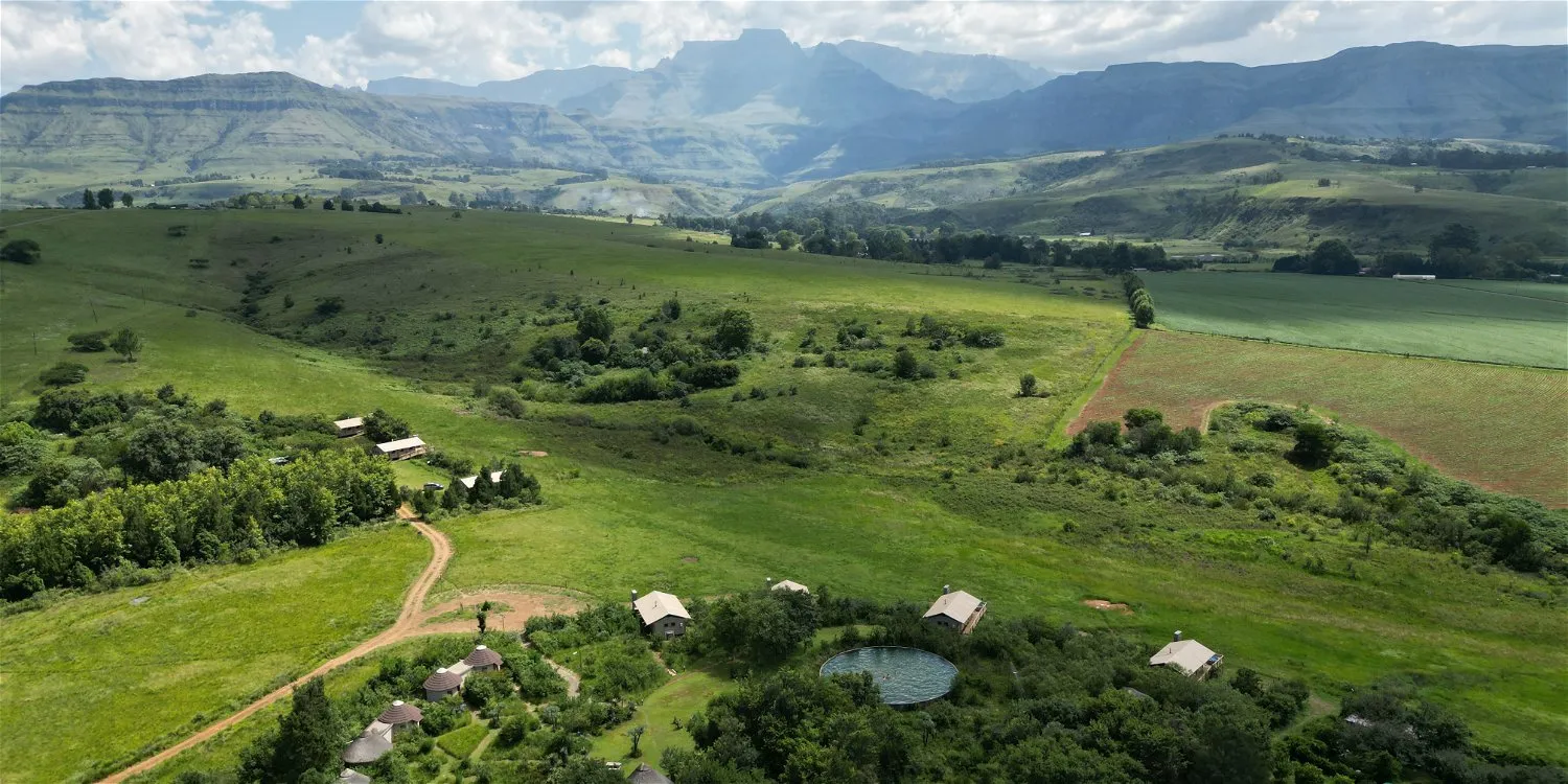 Aerial view of green hills small pond and scattered buildings in a valley