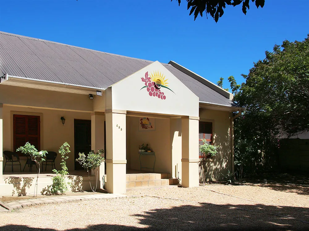 House with a sun and grapes mural outdoor seating and gravel driveway