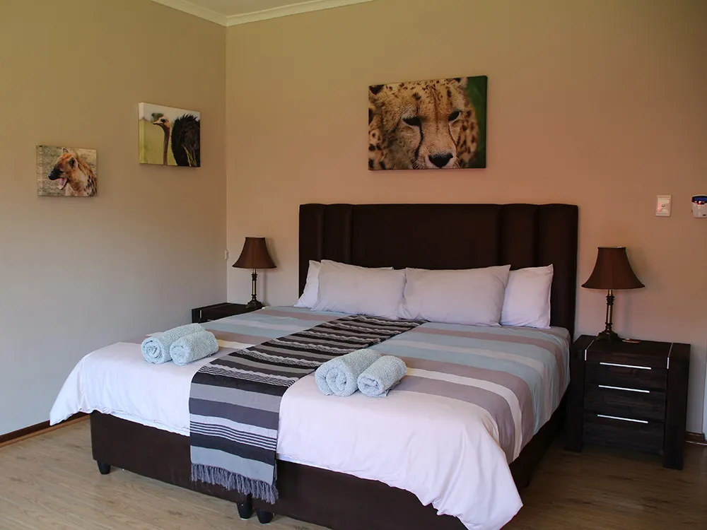 Bedroom with large bed cheetah picture above and bedside tables with lamps