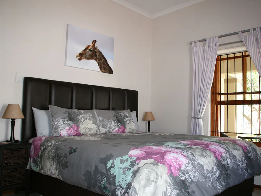 Bedroom with floral bedspread giraffe picture and window with curtains