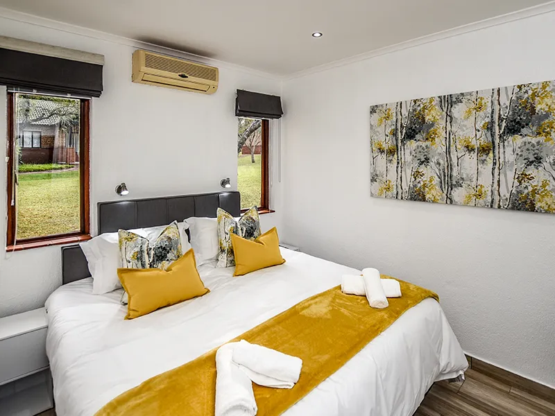 Cozy bedroom with a large bed yellow pillows and a nature view