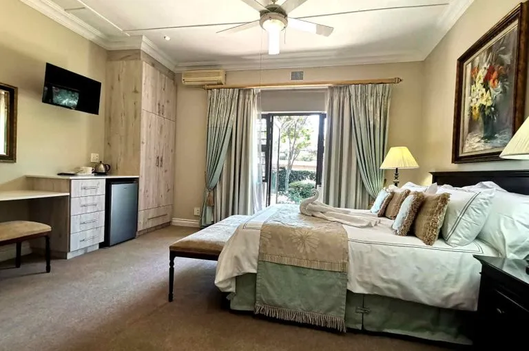 Bedroom with a large bed TV and garden view through large windows