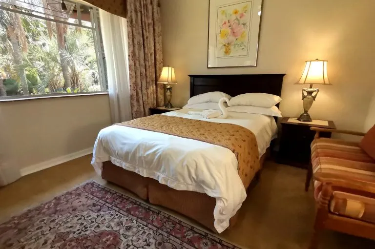 Cozy bedroom with a bed two lamps armchair and a window with curtains