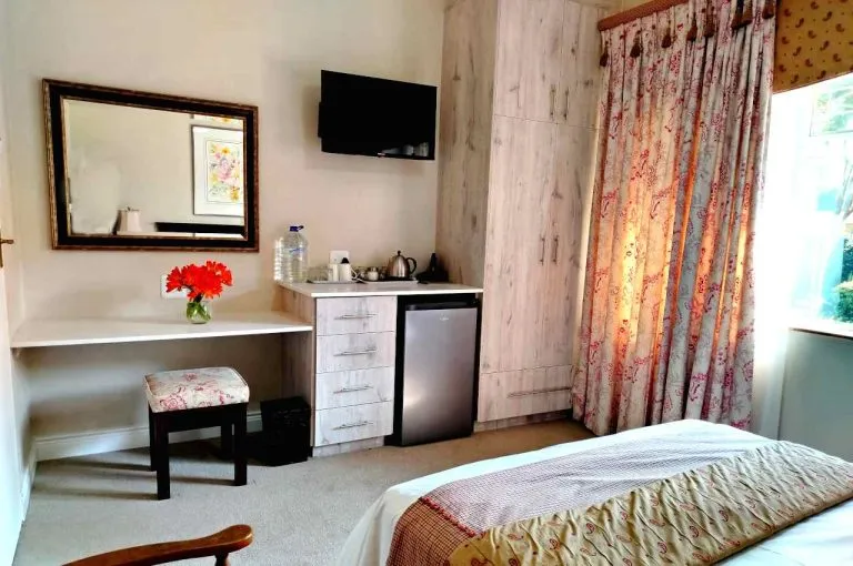 Cozy bedroom with bed desk mirror TV and floral curtains