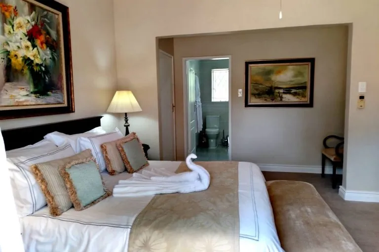 Bedroom with large bed pillows and a bathroom visible through an open door
