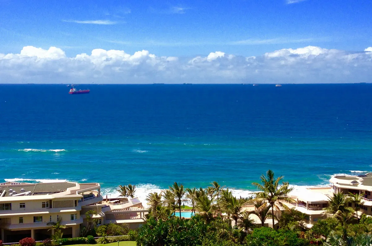 Ocean view with ships beach palm trees and resort buildings in the foreground