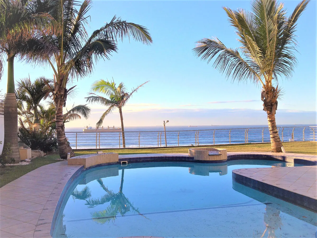 Swimming pool with palm trees and ocean view in the background