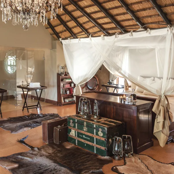 Luxury bedroom with fourposter bed chandelier and vintage trunks on wooden floor
