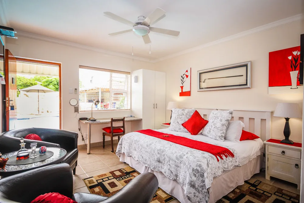 Cozy bedroom with red and white decor ceiling fan and outdoor view