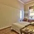 Bedroom with a bed wooden floor and large windows letting in natural light